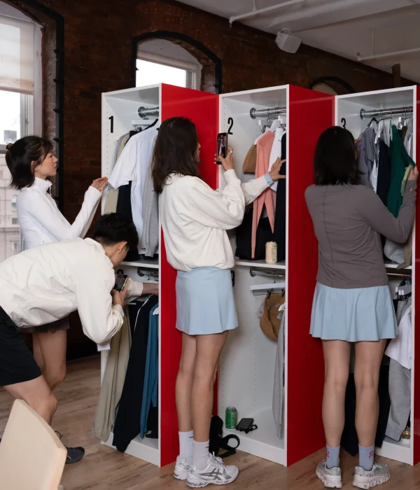 A group of four people interacting with clothing racks in a stylish indoor space.
