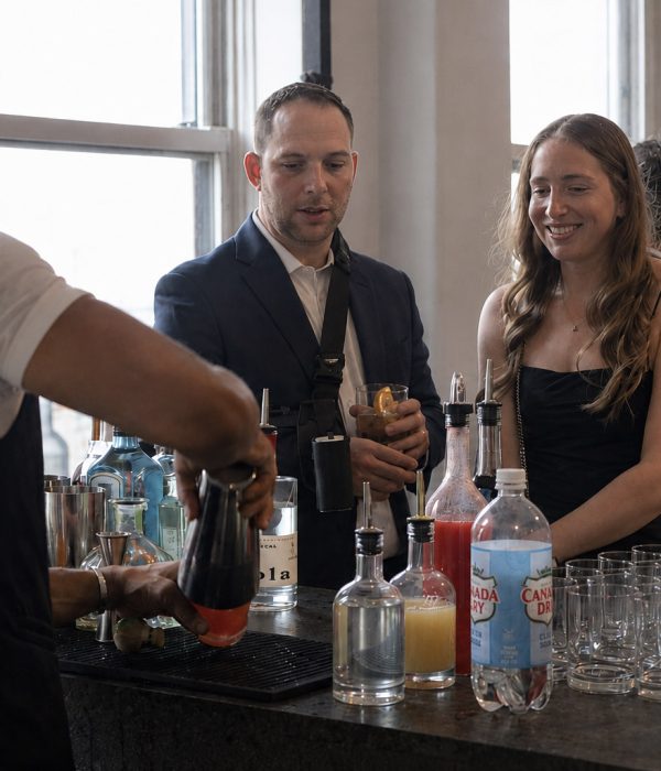 A bartender mixes drinks while guests enjoy beverages at a bar event.