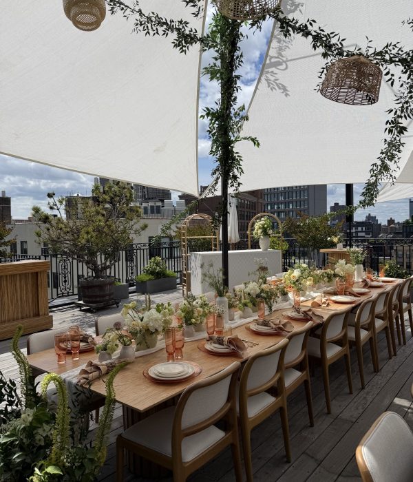 A beautifully arranged outdoor dining table with floral centerpieces and decorative elements under a canopy.