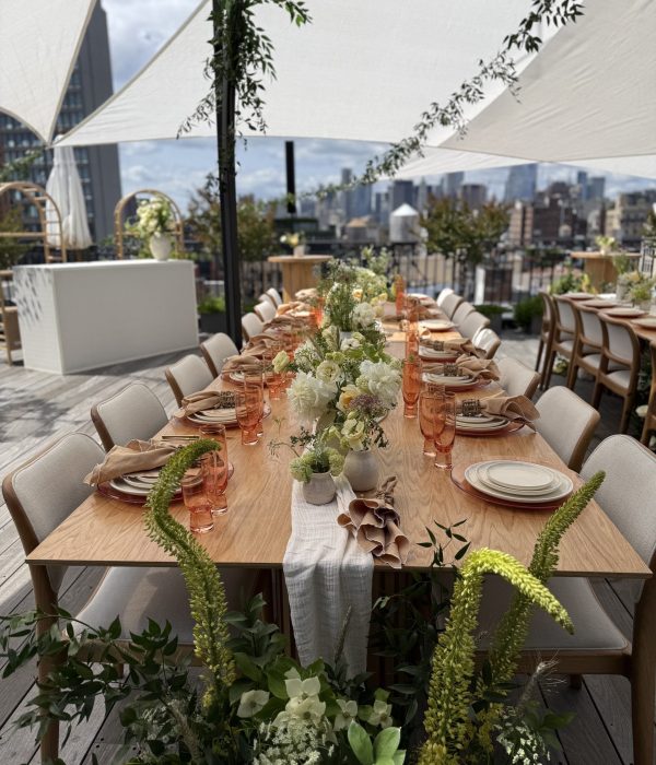 A beautifully arranged outdoor dining table with floral decorations and city skyline in the background.