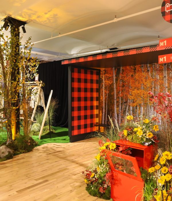 A vibrant indoor display featuring trees, a red and black checkered booth, and seasonal decor.